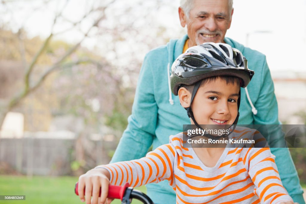 Older Hispanic man and grandson with bicycle