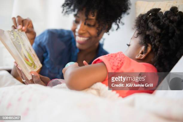 mother and daughter reading in bed - sharing stories stock pictures, royalty-free photos & images
