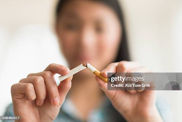 mixed race teenage girl breaking cigarette in half - produto relacionado com tabaco - fotografias e filmes do acervo