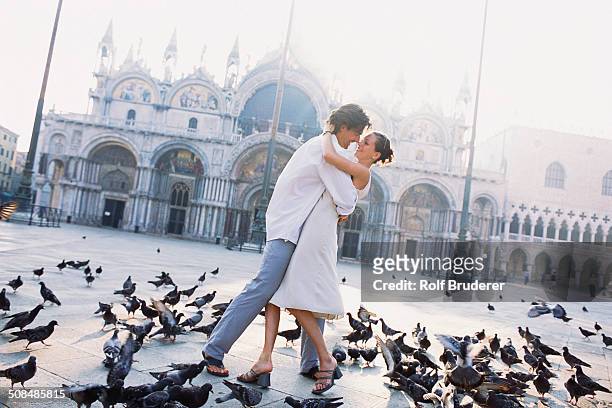 couple surrounded by pigeons in st. mark's square, venice, veneto, italy - venice with couple stock pictures, royalty-free photos & images