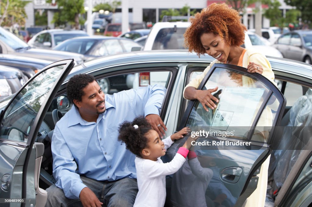 Black family admiring new car