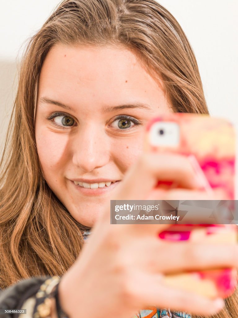 Caucasian teenage girl taking picture with cell phone