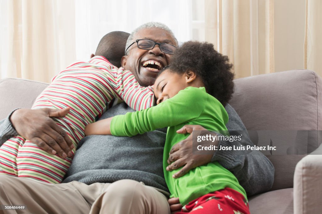 Older man hugging grandchildren on sofa