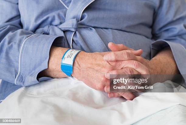 senior caucasian man sitting in hospital bed - namensband stock-fotos und bilder