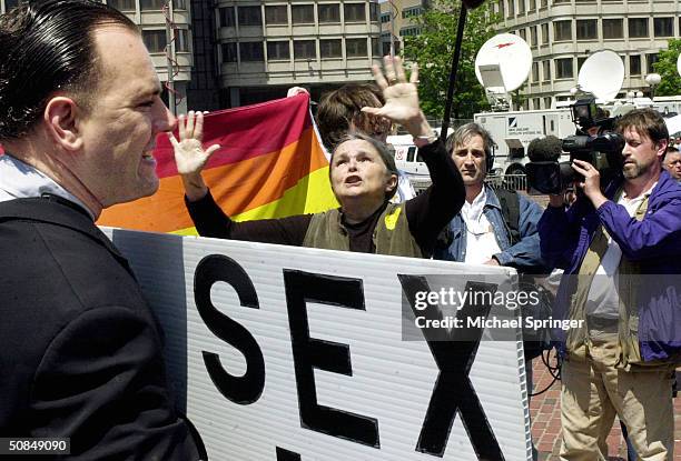 Woman raises her arms in prayer as news cameramen look on during a demonstration against same-sex marriage outside City Hall May 17, 2004 in Boston,...