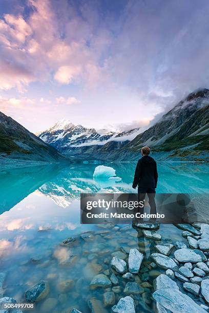 landscape: hiker looking at mt cook from lake with iceberg, new zealand - mt cook stock pictures, royalty-free photos & images