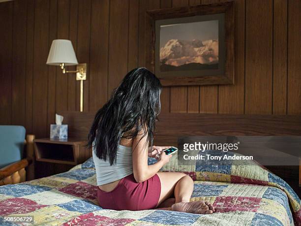 Young woman with mobile phone on hotel bed