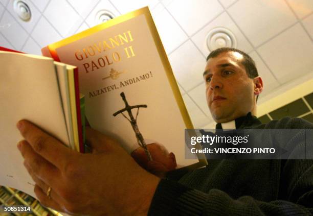 Priest reads Pope John Paul II's new book "Alzatevi, andiamo" in a bookshop at the Vatican 18 May 2004. The pontiff, who celebrates 18 May 2004 his...