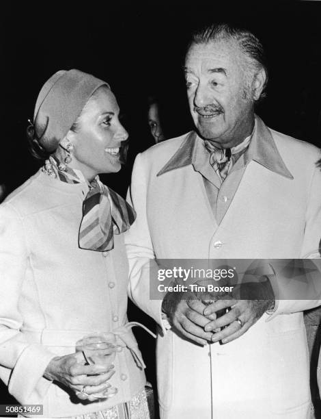 American real estate developer William J Levitt and his French-born wife Simone laugh and hold drinks at a party, 1970s.