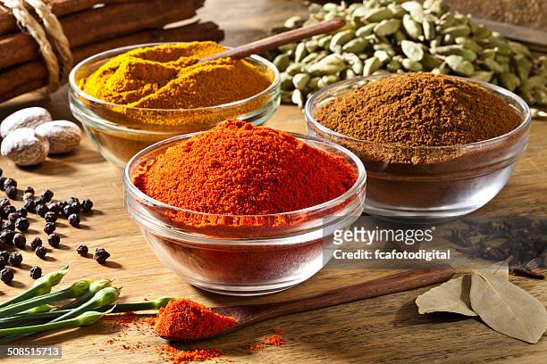 three bowls filled with spices on rustic wood table - spice stock pictures, royalty-free photos & images