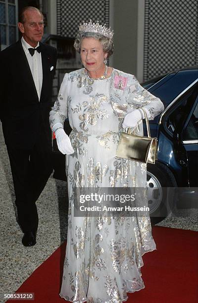 Queen Elizabeth II, wearing a white evening dress embroidered with silver by designer Ian Thomas, the Queen Mary's Girls of Great Britain and Ireland...