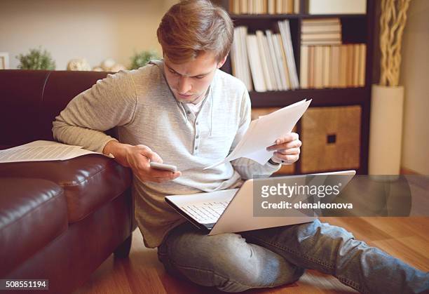 attractive young man in home interior - filing documents stock pictures, royalty-free photos & images