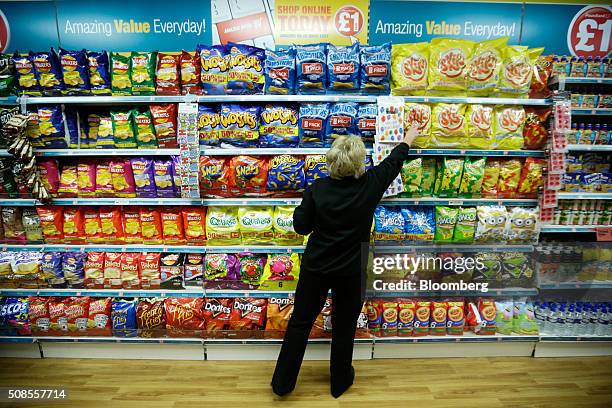 An employee stacks the shelves with snack products at a Poundland Group Plc store in Leigh, U.K., on Thursday, Feb. 4, 2016. U.K. Like for like sales...