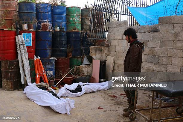 Man stands next to the bodies of victims killed earlier in the day following a reported attack by airstrike on the Sakhour eastern neighbourhood, in...