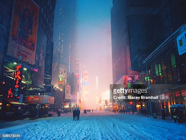 people walking in the streets of times square after they are closed to traffic during a blizzard - new york city snow stock pictures, royalty-free photos & images