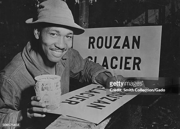 African-American soldier painting a sign that reads Rouzan Glacier, as part of the ALCAN highway project, 1942. From the New York Public Library. .