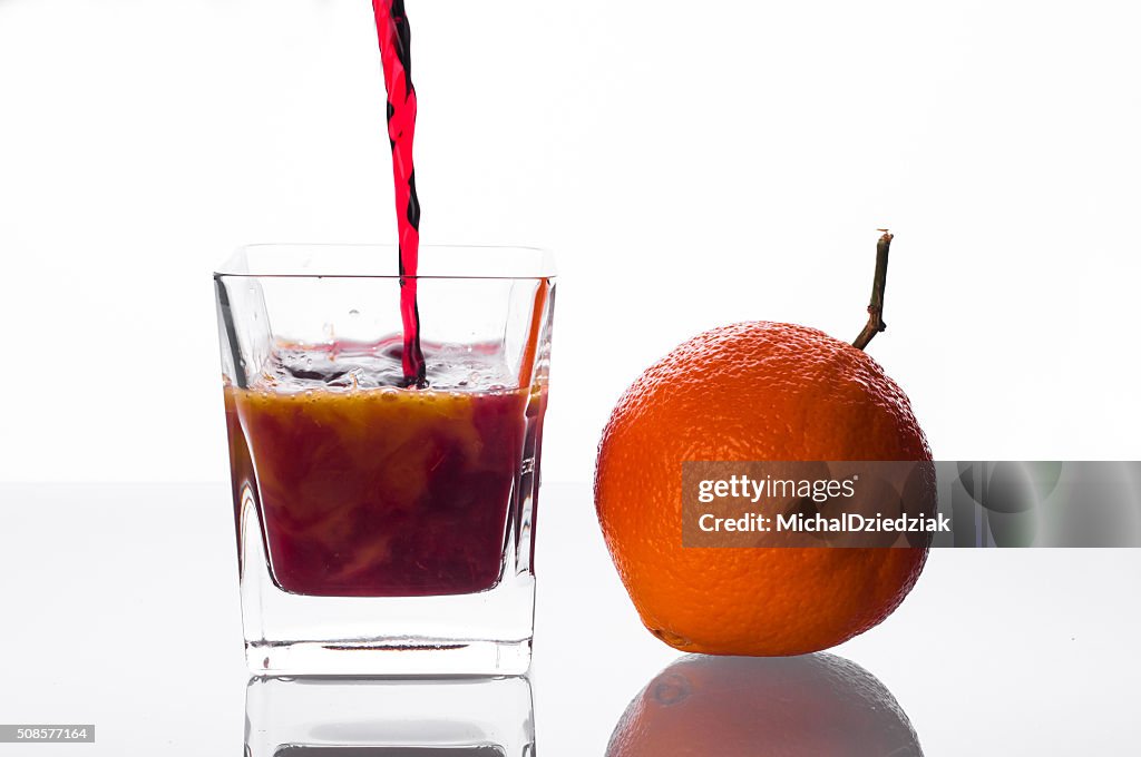 Blackcurrant juice pouring into glass with orange juice