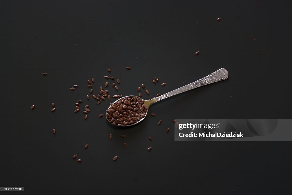 Linseed on metal spoon on dark wooden table