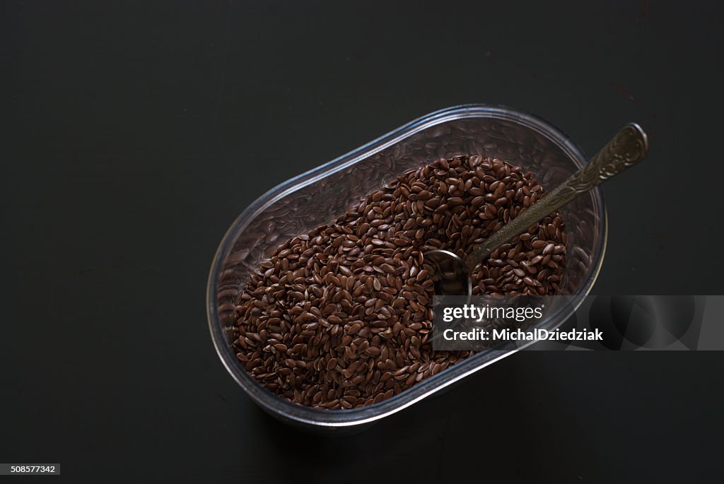 Linseed in a plastic box on dark wooden table