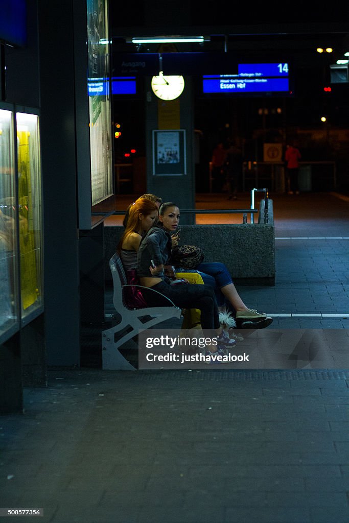 Girls on bench in station at summer night