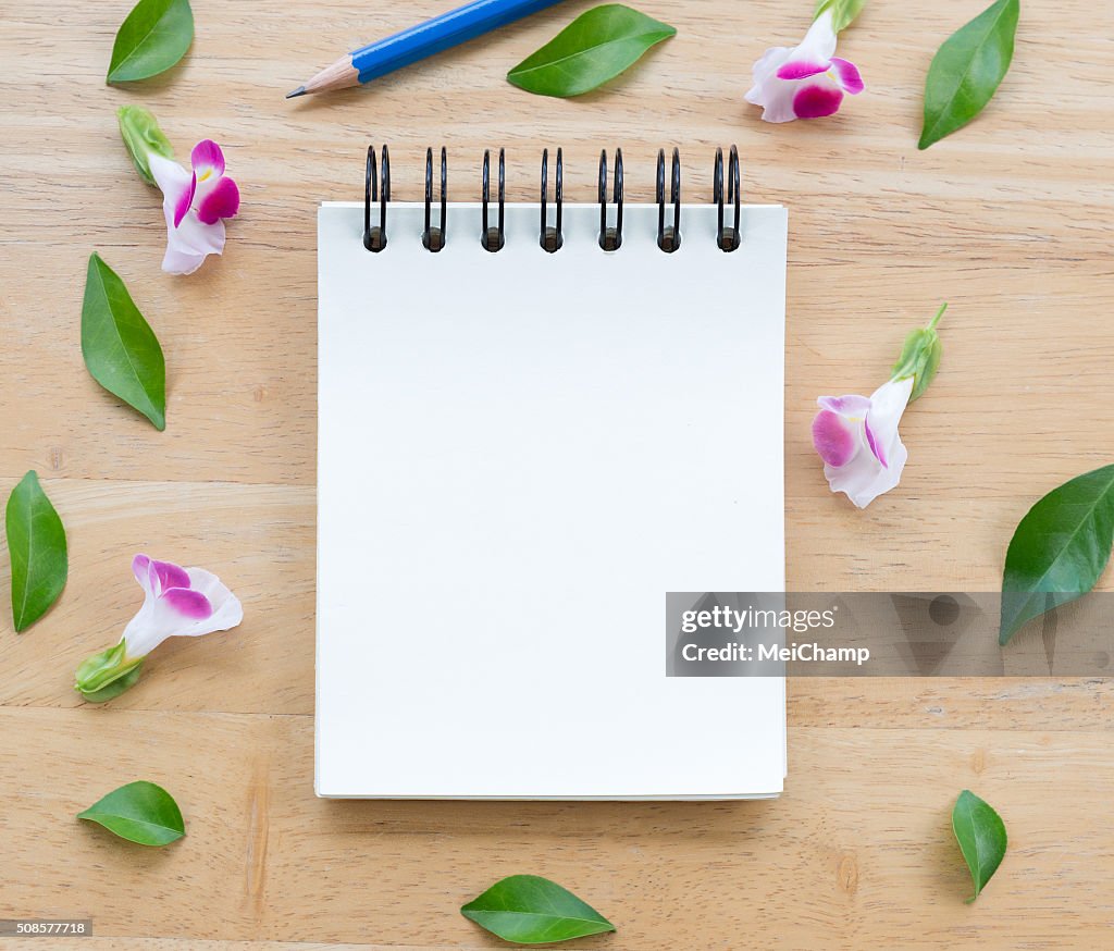 Blank notebook on wood background with flowers