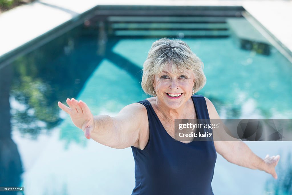 Senior woman smiling, exercising by swimming pool