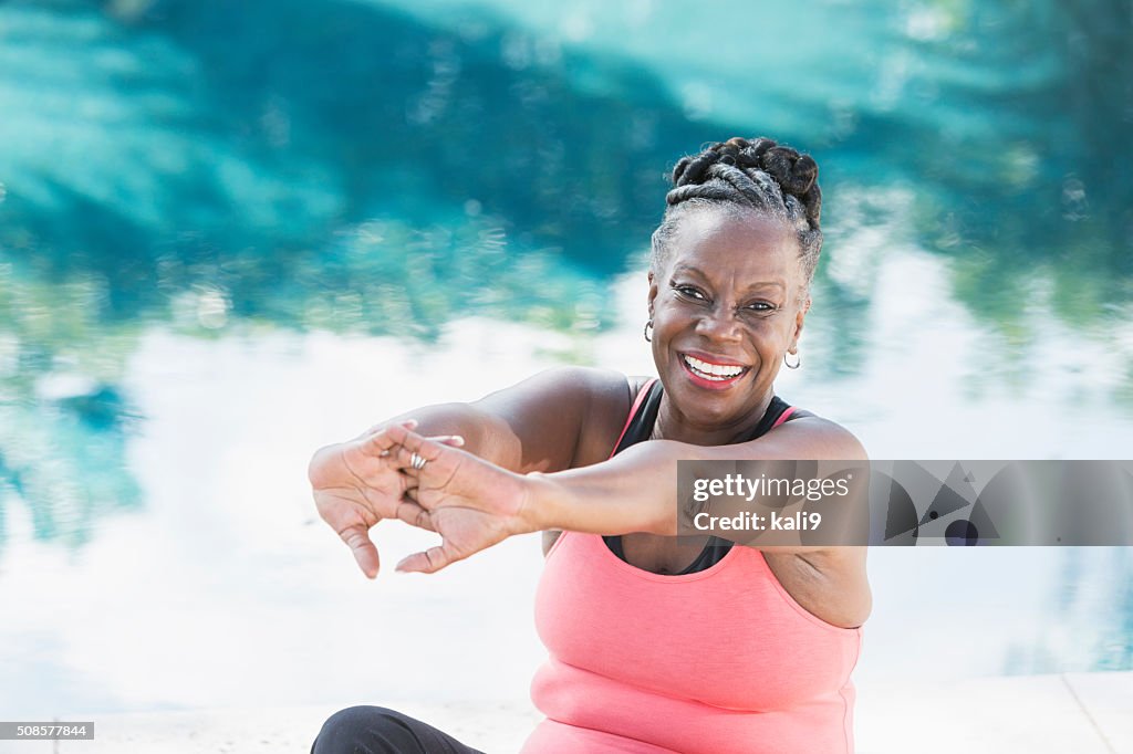 Madura mulher afro-americana a fazer alongamentos de Piscina