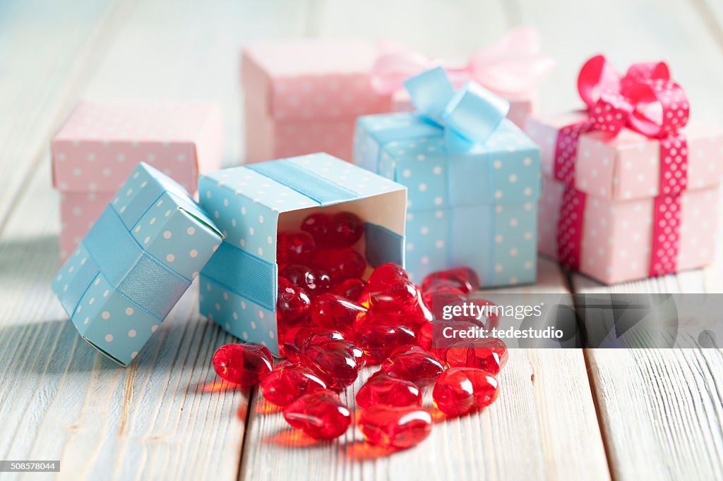 Rote Herzen und bunten Geschenkboxen auf hölzerner Hintergrund
