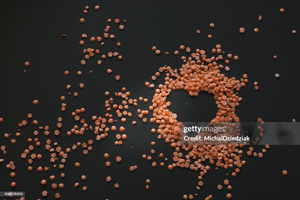 Red lentil heart on dark wooden table