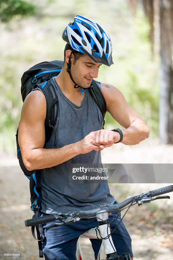 Hombre montando una bicicleta y usando un reloj inteligente