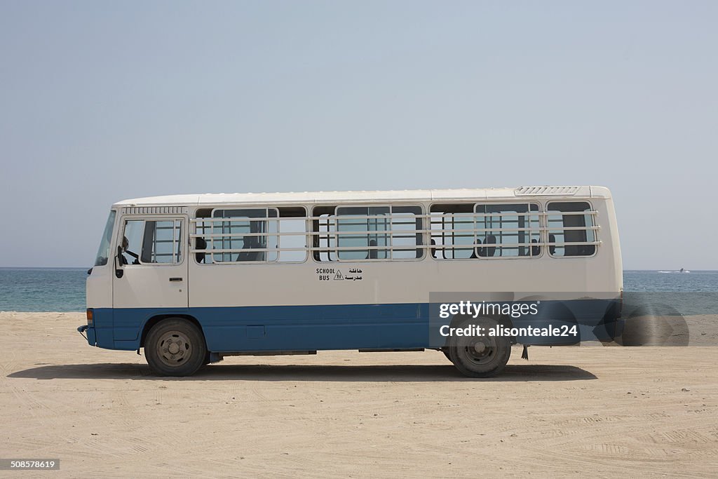 An empty school bus parked on the sand, Dibba, Oman