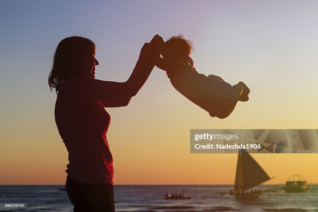 Glückliche Mutter und baby Spaß am sunset beach