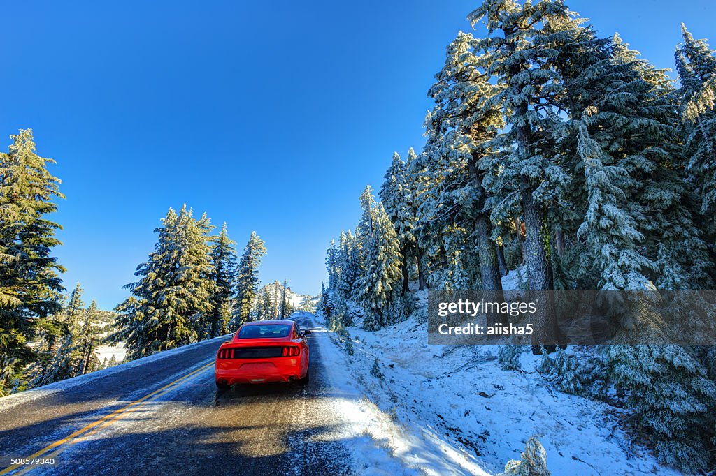 Red car on snowy and icy winter road