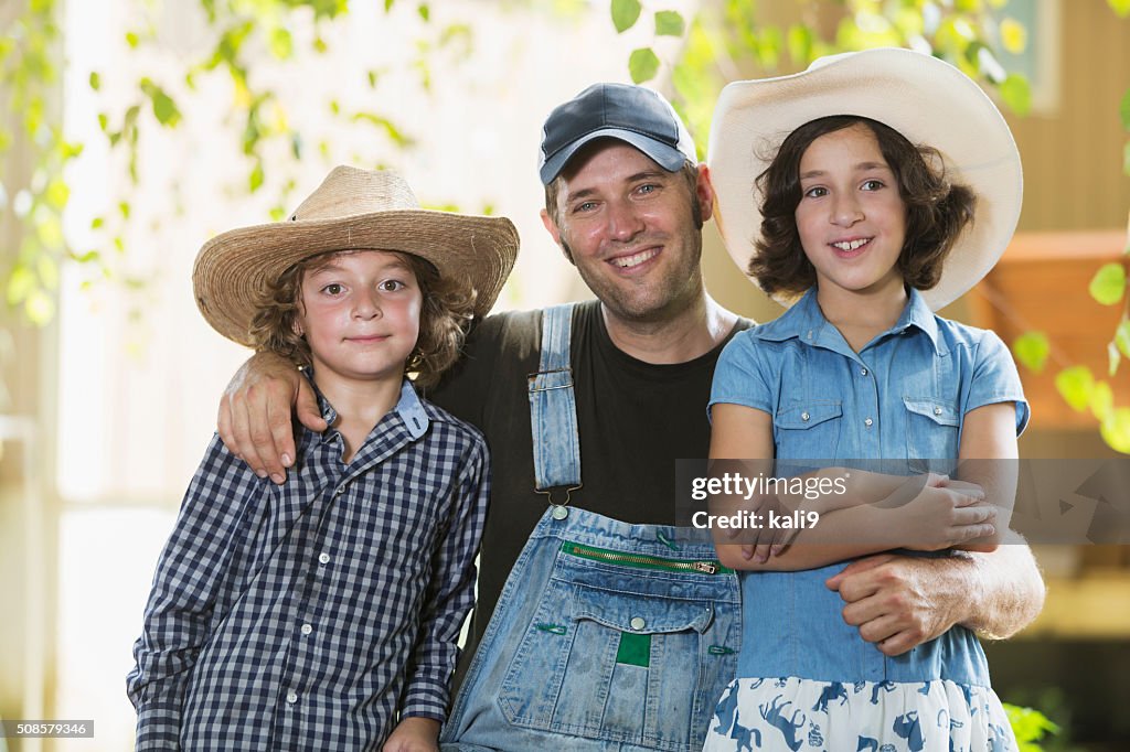 Father and children on family farm smiling at camera