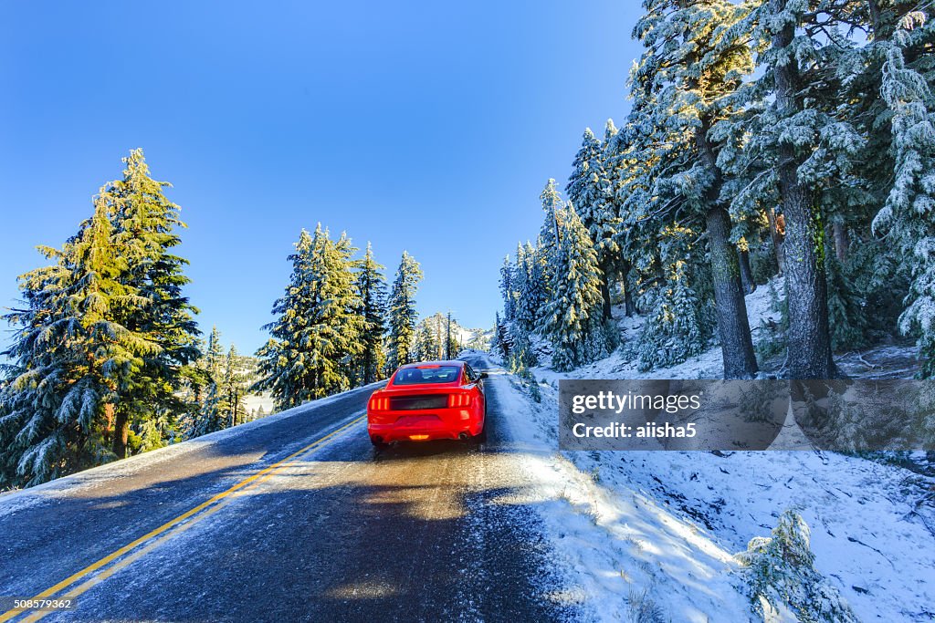 Red car on snowy and icy winter road