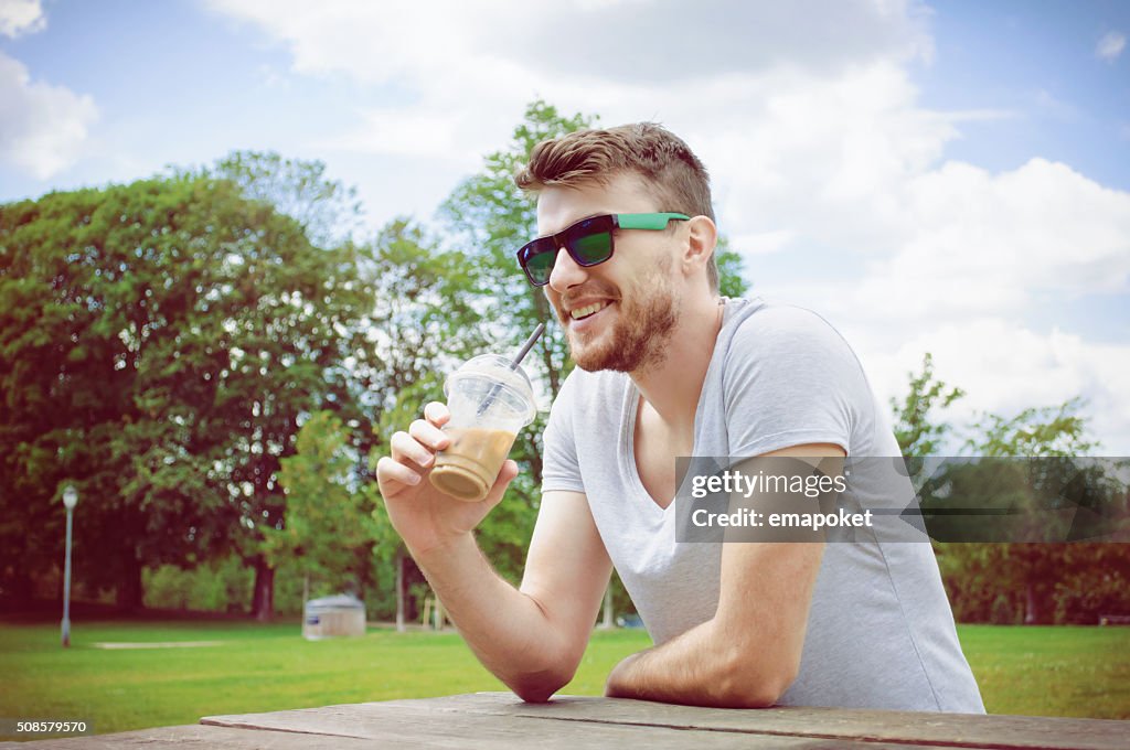 Handsome man drinking coffee in park