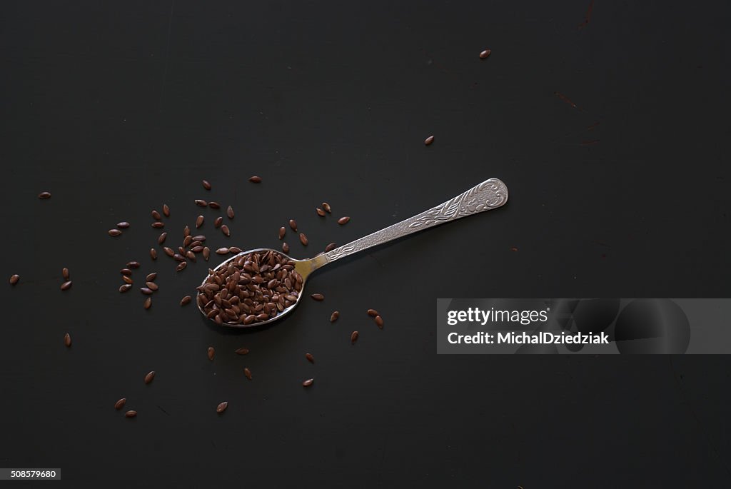 Linseed on metal spoon on dark wooden table