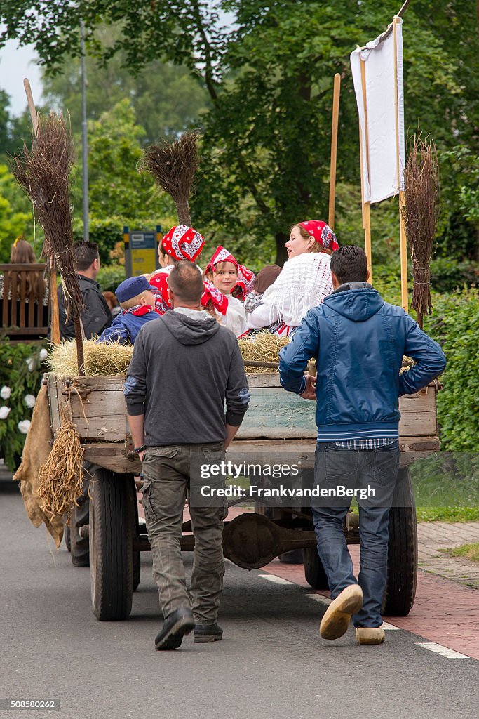Dutch men on clogs behind a cart with dressedup people