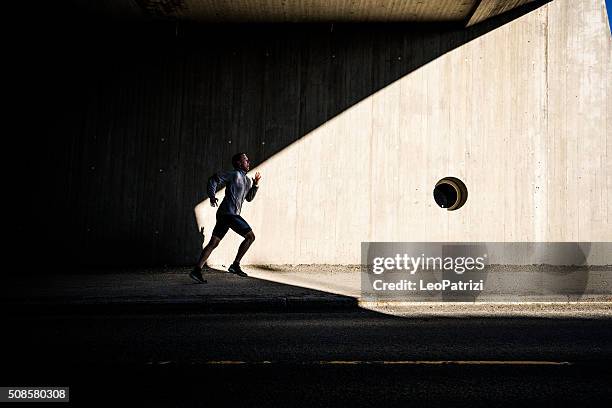 mann läuft in der stadt in am frühen morgen - running shadow stock-fotos und bilder