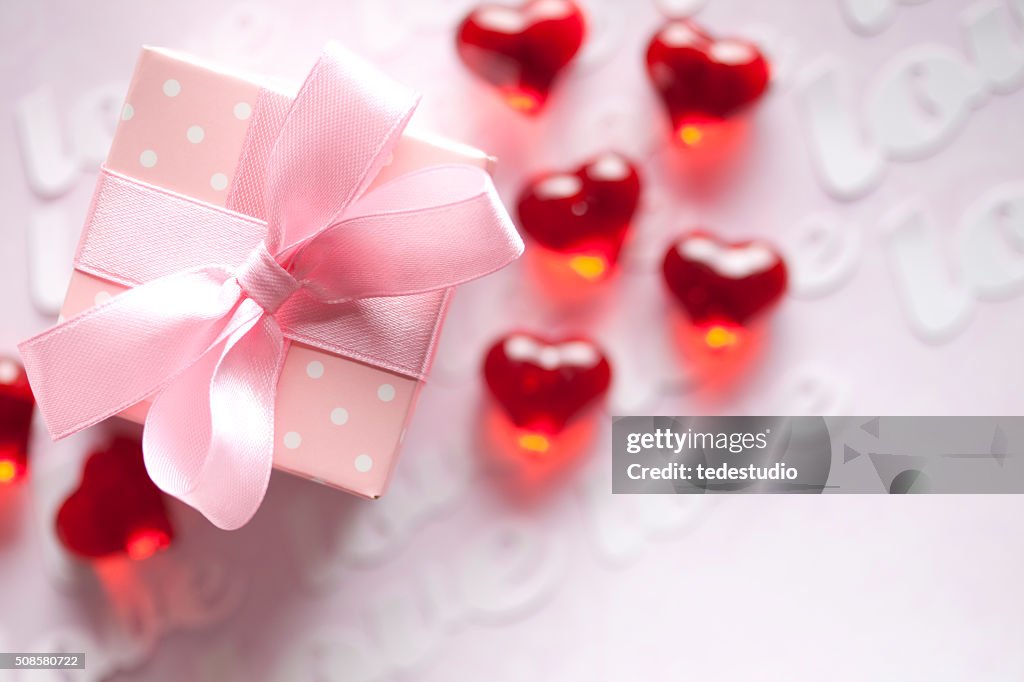 Red hearts and gift box on pink background