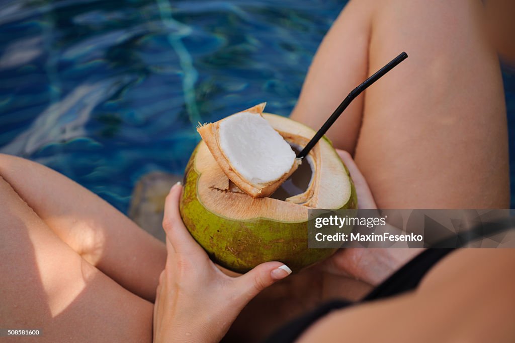 Mädchen mit Kokosnuss im Swimmingpool