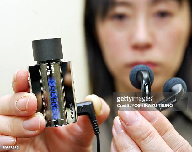 Japan's electronics giant Toshiba employee Junko Furuta displays prototype model of a super compact audio player, equipped with the world's smallest...