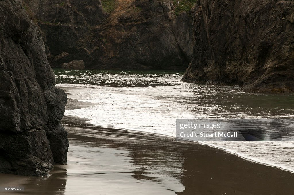 Tide washes up between rocks on beach