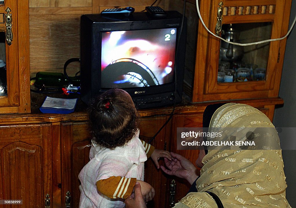 A Moroccan woman and her baby watch tele