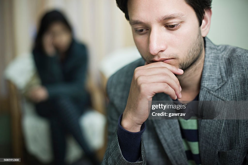 Sad couple, selective focus is on young man.