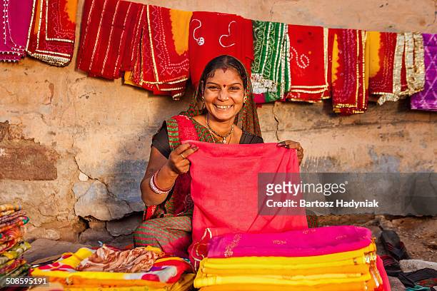 indian woman selling colorful fabrics on market - woman in red sari stock-fotos und bilder