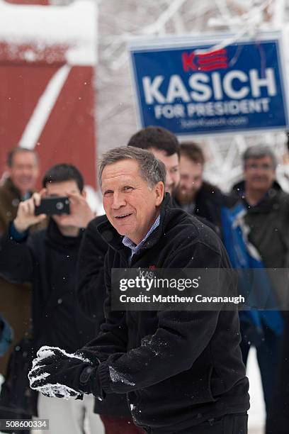 Ohio Governor and Republican presidential candidate John Kasich smiles during a snowball fight with his staff following a town hall style meeting on...