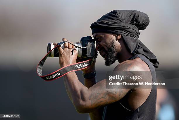 Injured player Charles Tillman of the Carolina Panthers takes photographs of his teammates participating in drills during practice prior to Super...