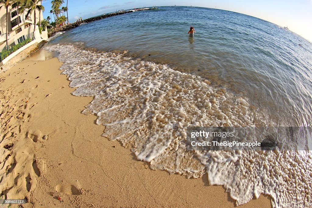 Young girl plays in ocean waves near beach