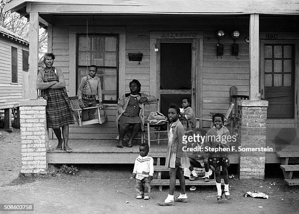 An African-American family sit on the porch of their home watching the 1965 Selma to Montgomery marchers pass by on route 80, Jefferson Davis Highway...